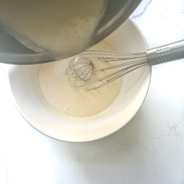 Pouring all the milk mixture to the eggs in a large mixing bowl.