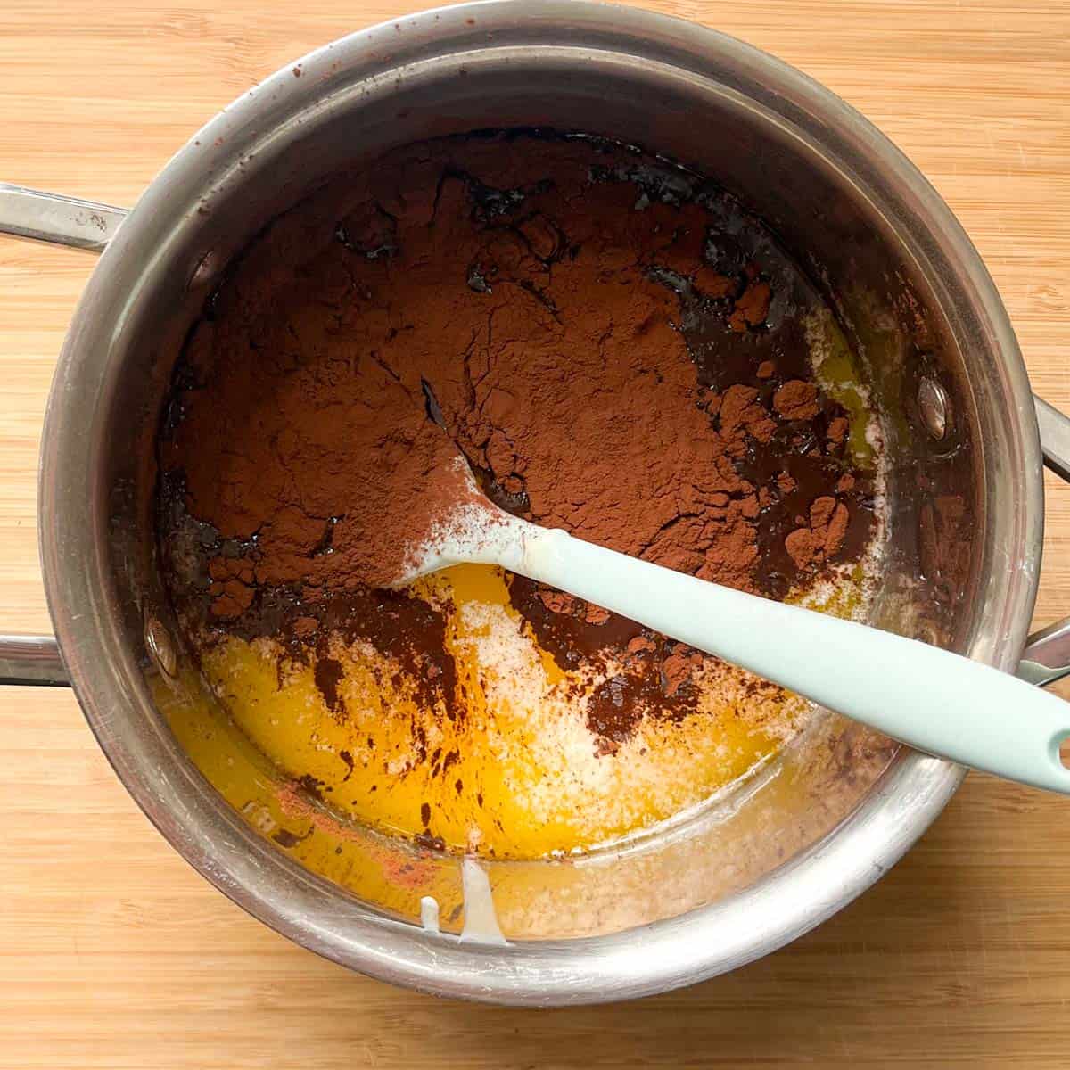 Cocoa powder added to melted butter in a small saucepan.