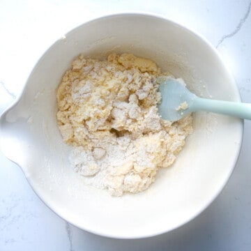 Flour folded into cake batter in a large mixing bowl.