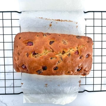 Baked sultana cake on a black wire cooling rack.