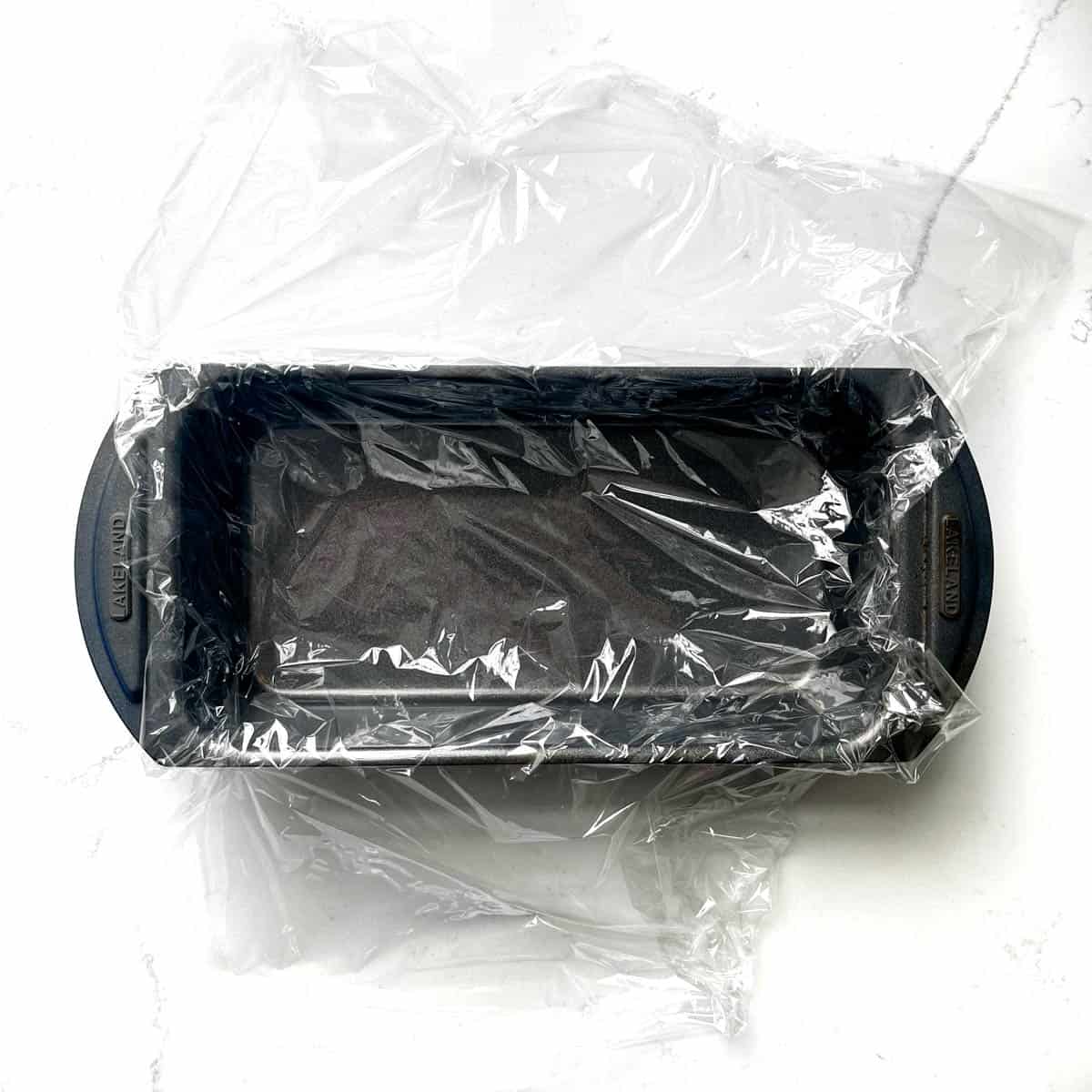 A loaf tin lined with plastic wrap. 