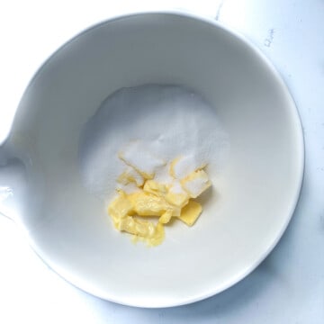 Sugar and butter in a large white mixing bowl.