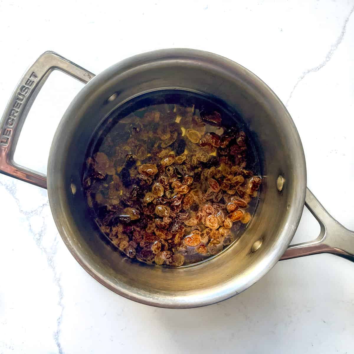 Sultanas added to a saucepan, covered with water.