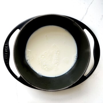 Milk added to a black cast iron saucepan.
