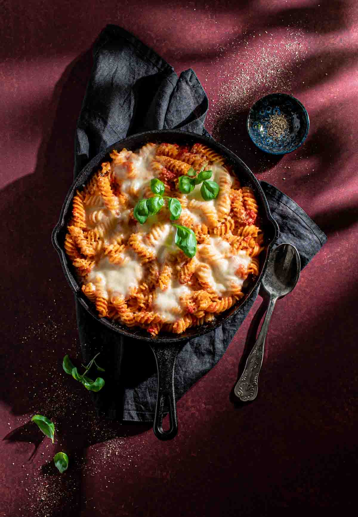 Pasta alla sorrentina in a cast iron frying pan resting on a grey napkin.