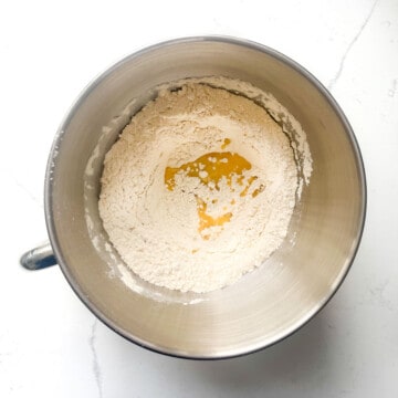 Adding melted butter to flour in a large mixing bowl.