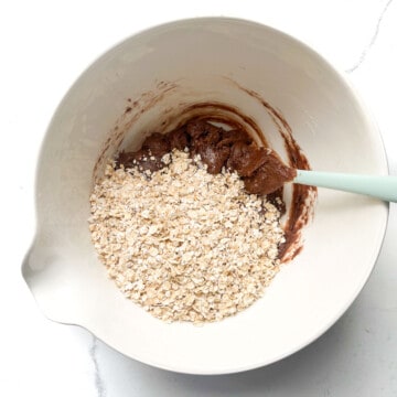 Oats added to chocolate mixture in a large white bowl.