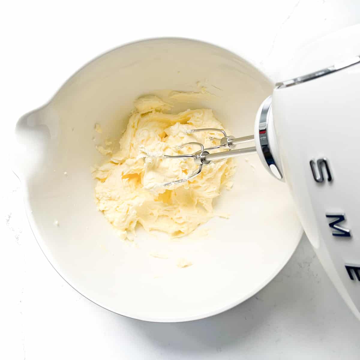 Beating butter and sugar together with an electric hand whisk.