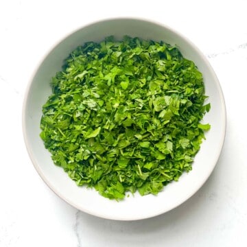 Chopped parsley for the Taboule in a white bowl.
