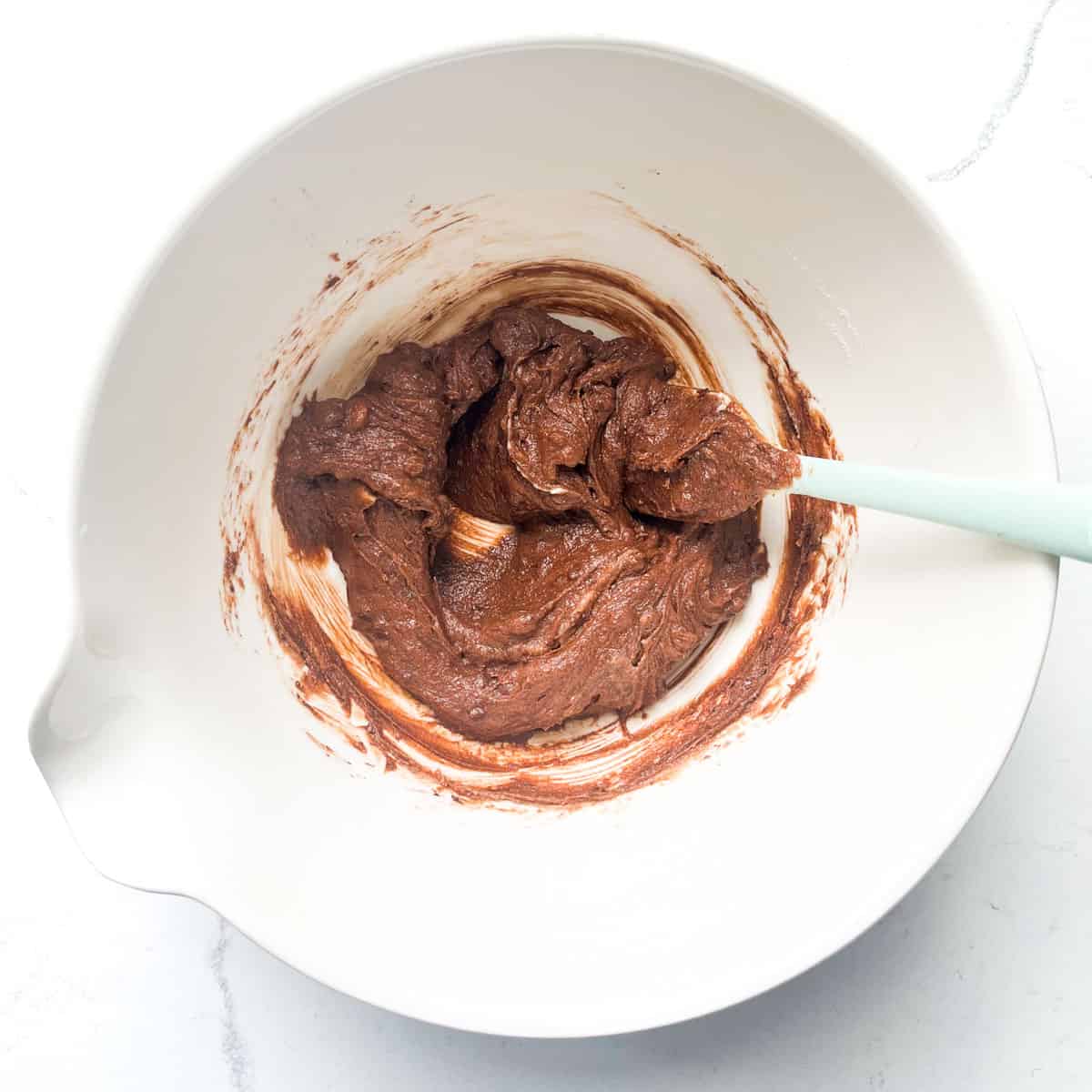 Chocolate and coffee paste mixed in with butter and sugar in a large white bowl.