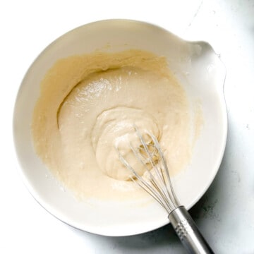 Mixing the dry ingredients with half the milk and oil in a large white bowl.