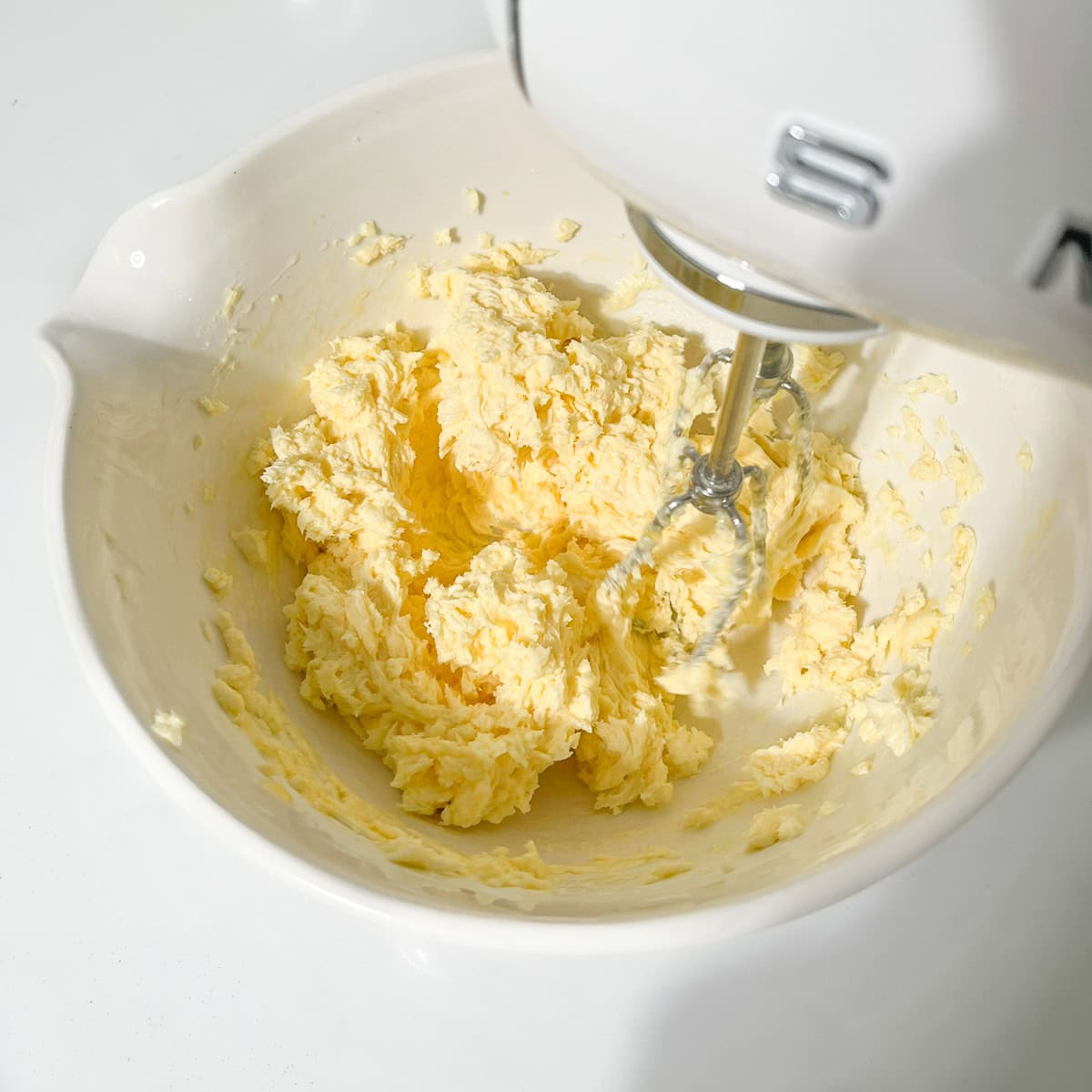 Beating the egg into the butter and sugar mixture with an electric hand mixer.