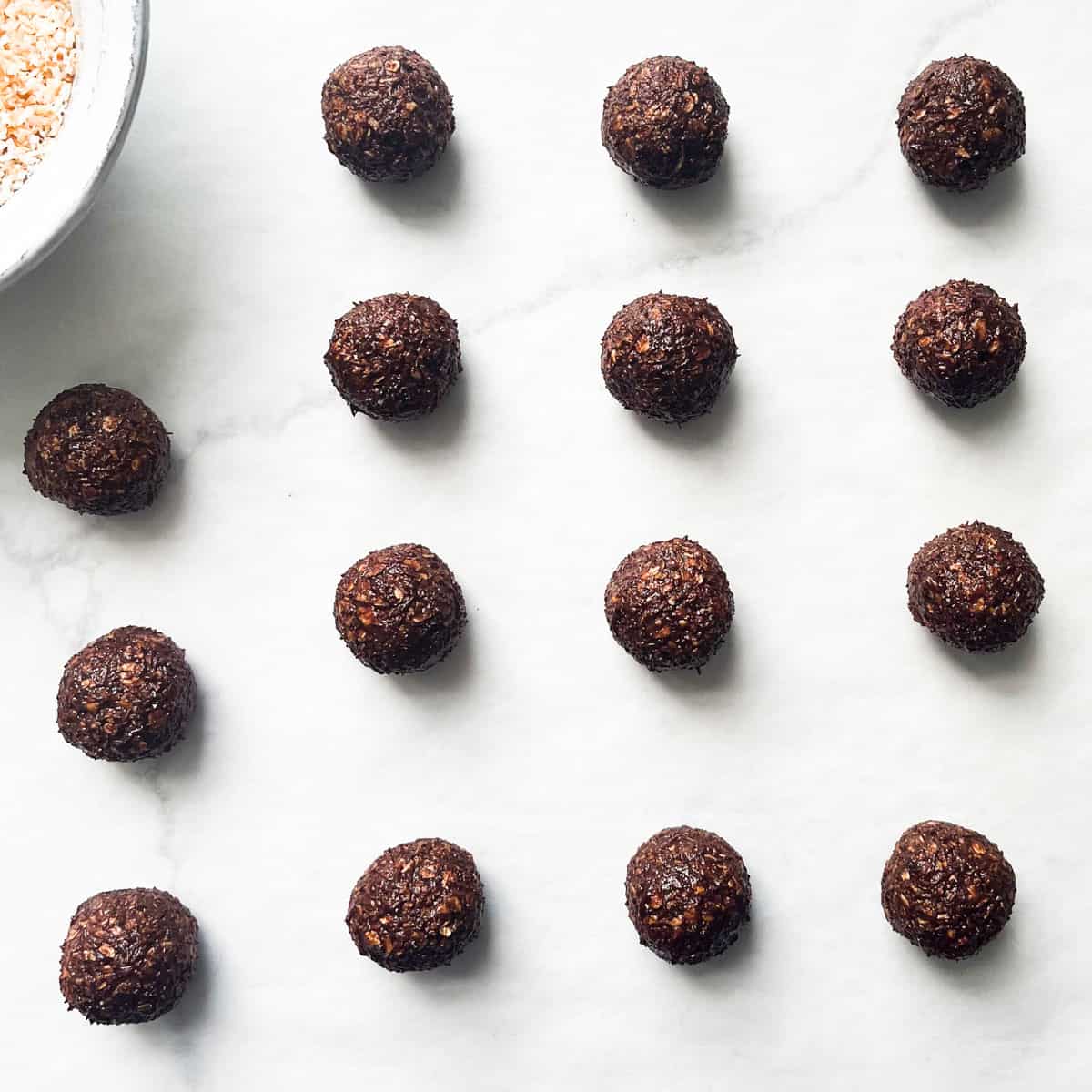 Chokladbollar on parchment paper, rolled into balls but not dipped in coconut yet.