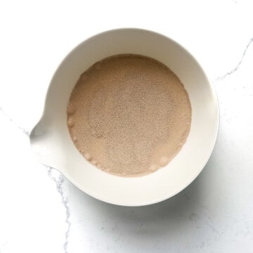Yeast added to warm milk in a small white bowl. 