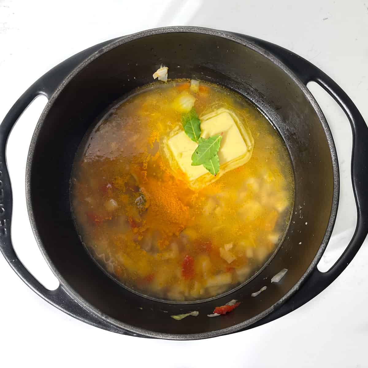 Adding chicken stock to the fried onions and pepper for the Arroz Amarillo.