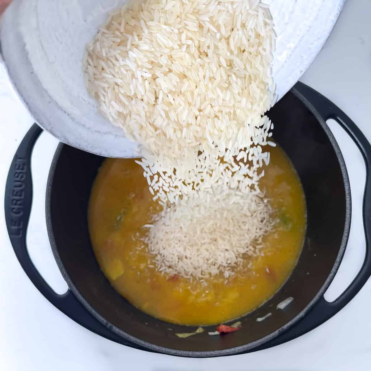 Adding rice to the heavy-based-saucepan.