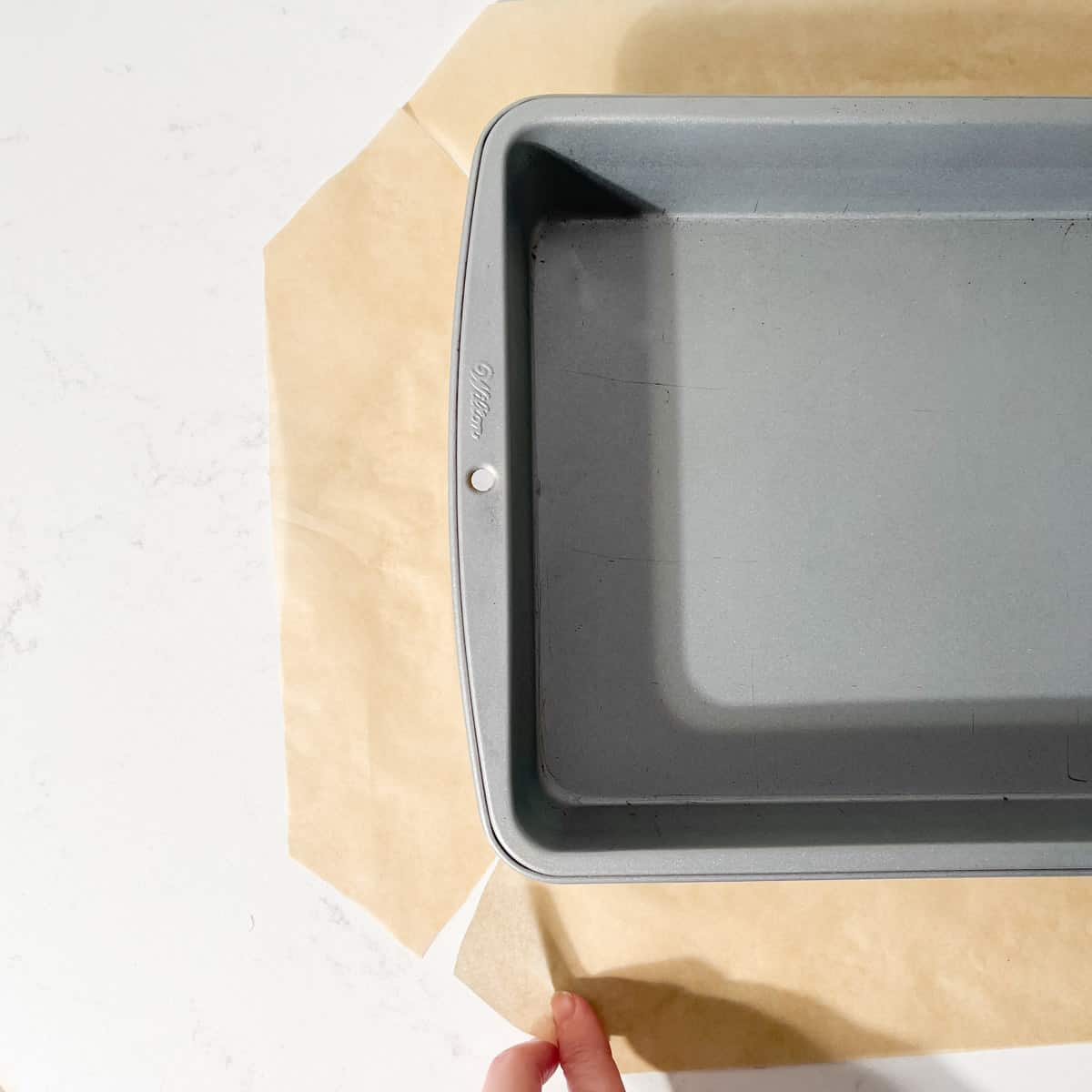 A baking tin on a piece of baking paper with slits cut into each corner of the paper to fit easily into the tin.