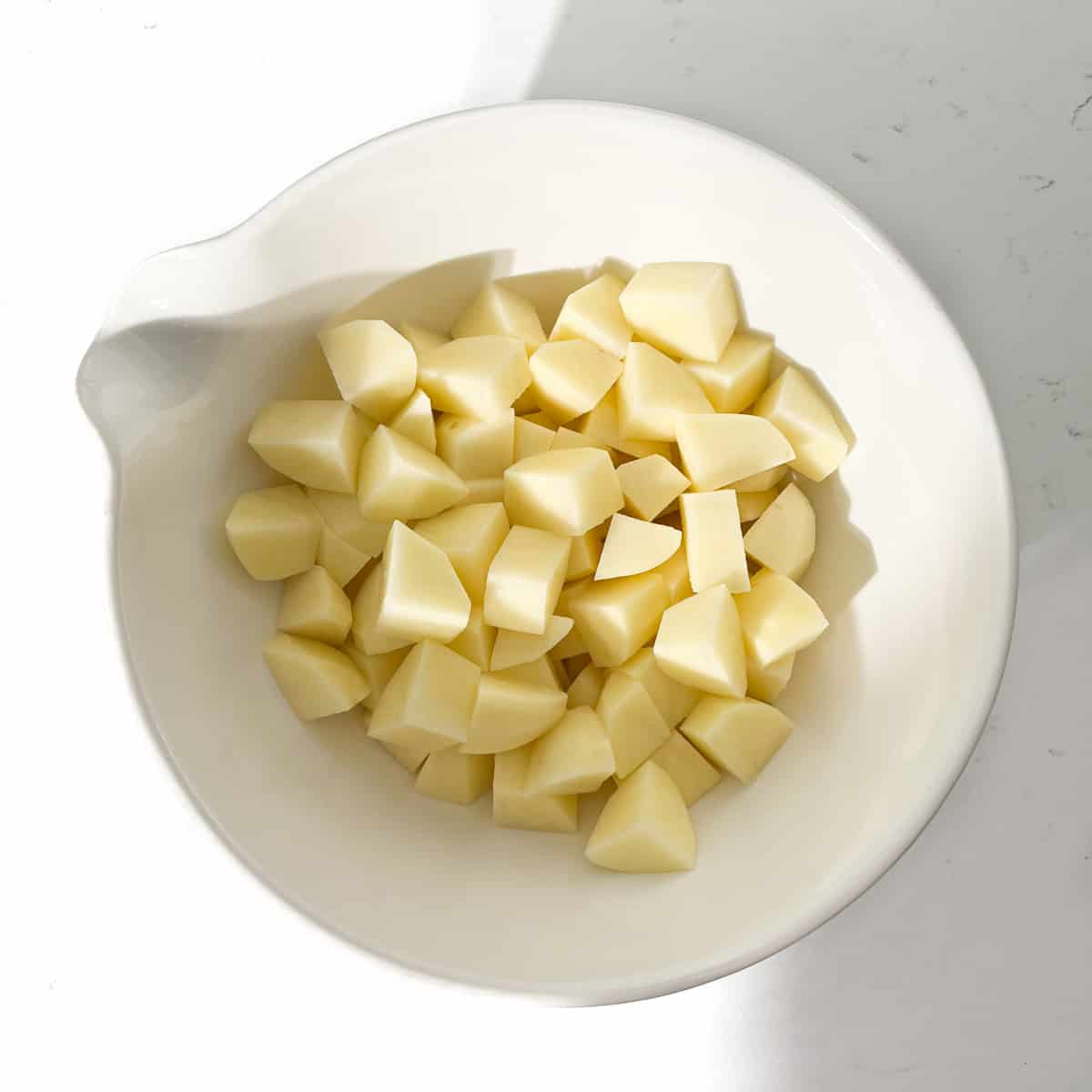 Potato cubes in a large white bowl.