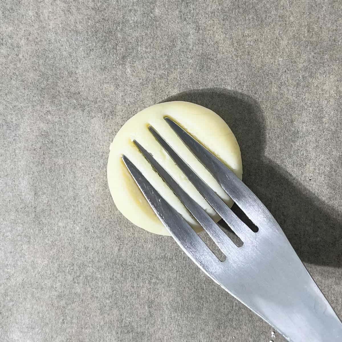 Flattening a dough ball with a fork.