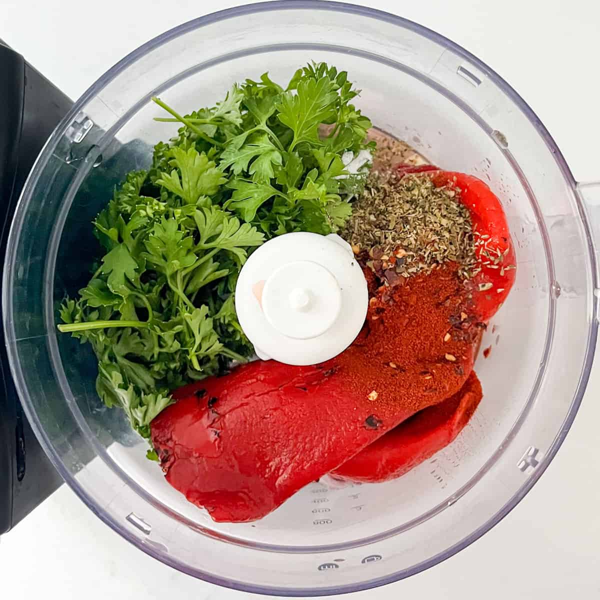 Red chimichurri ingredients in a food processor, ready to be chopped.