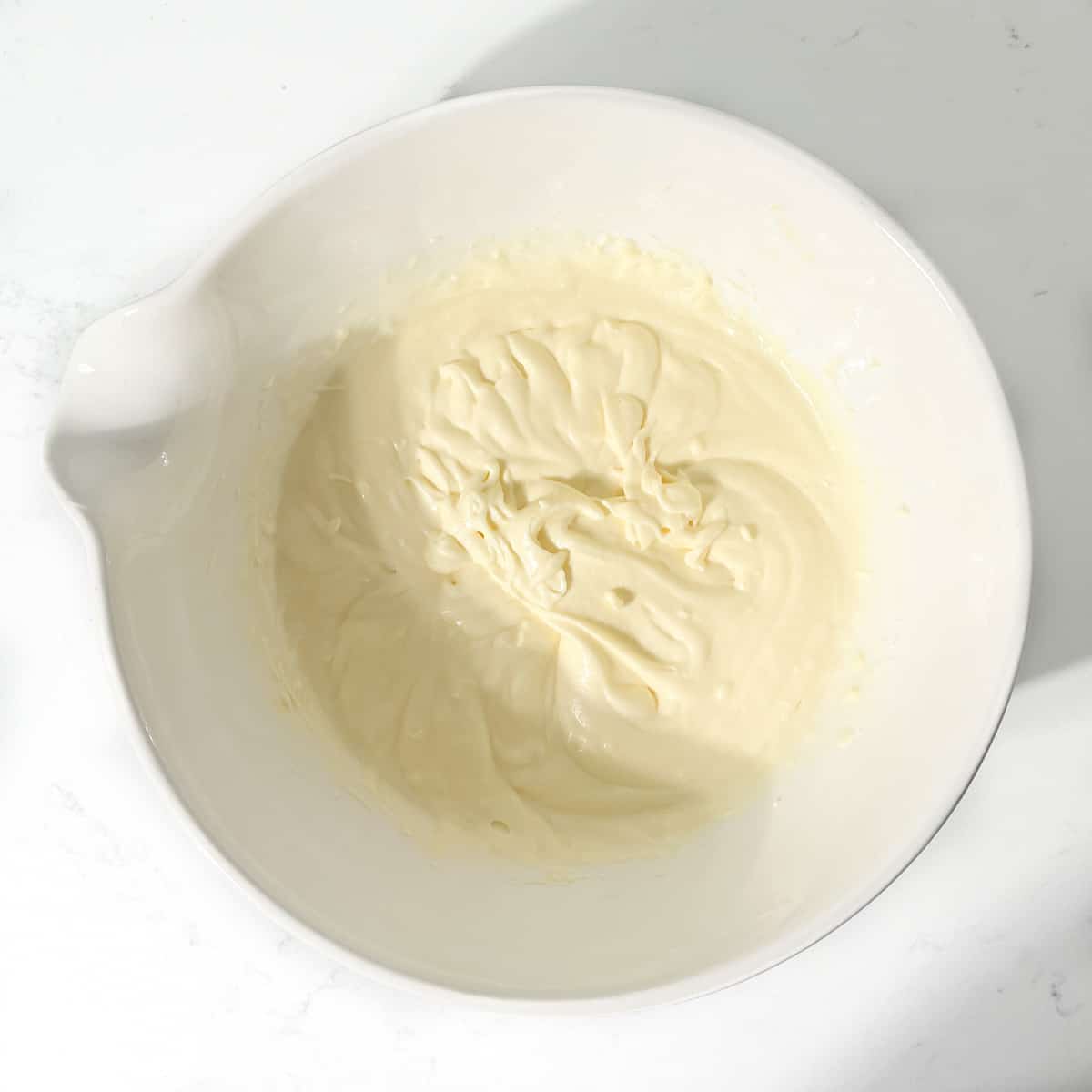 Mixed condensed milk and butter in a large white bowl.