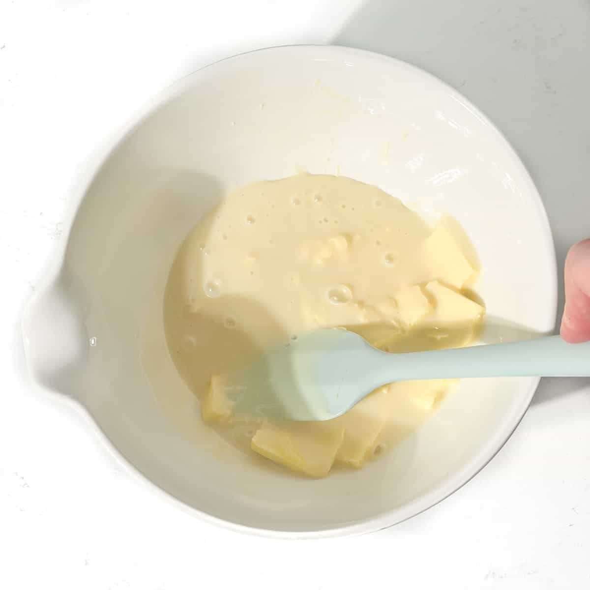 Mixing the butter and condensed milk for the sequilhos by hand with a spatula.