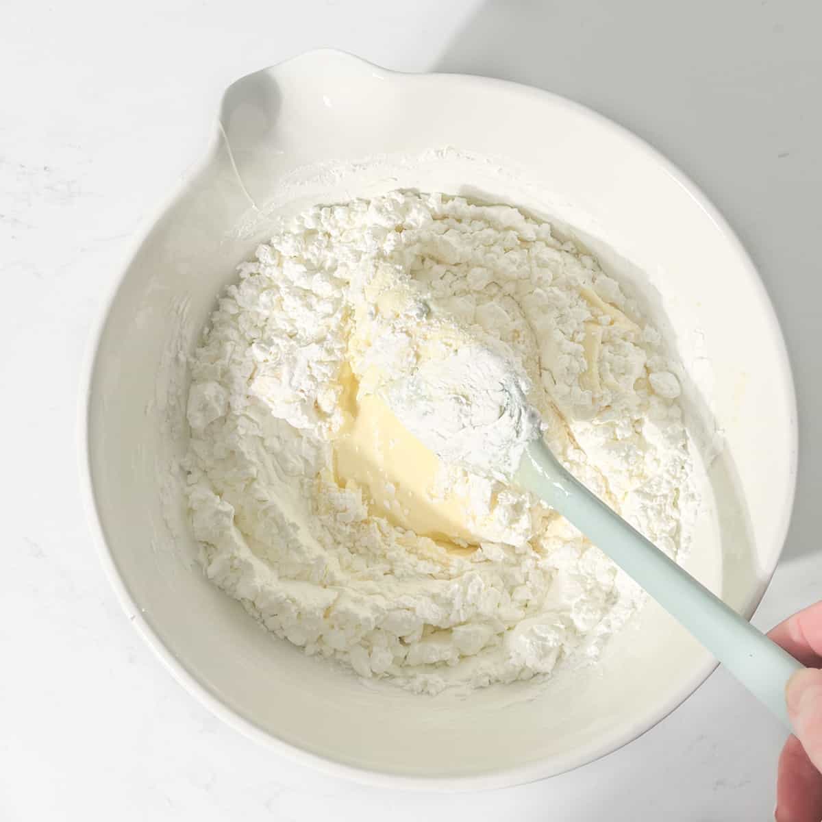 Folding cornflour into the butter and condensed milk for sequilho dough.