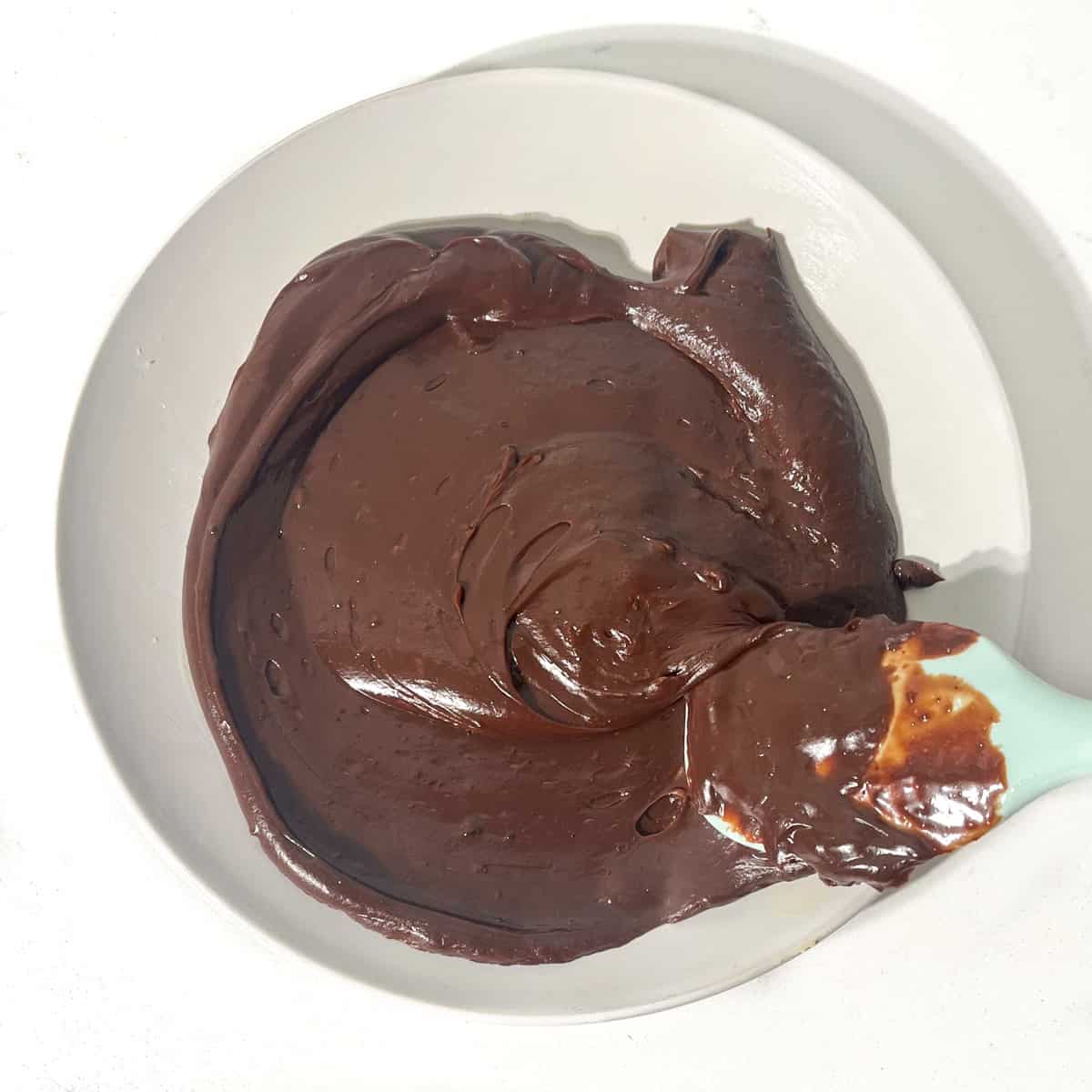 The brigadeiro mixture being spread out on a buttered plate with a spatula.