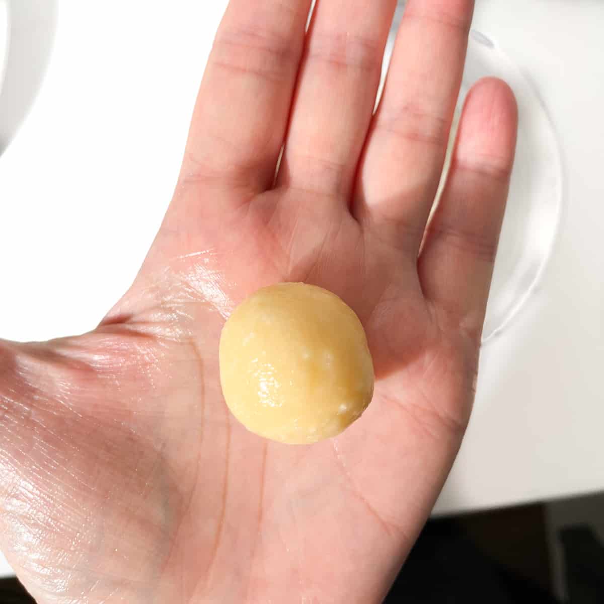 A hand holding a rolled Beijinhos ball.