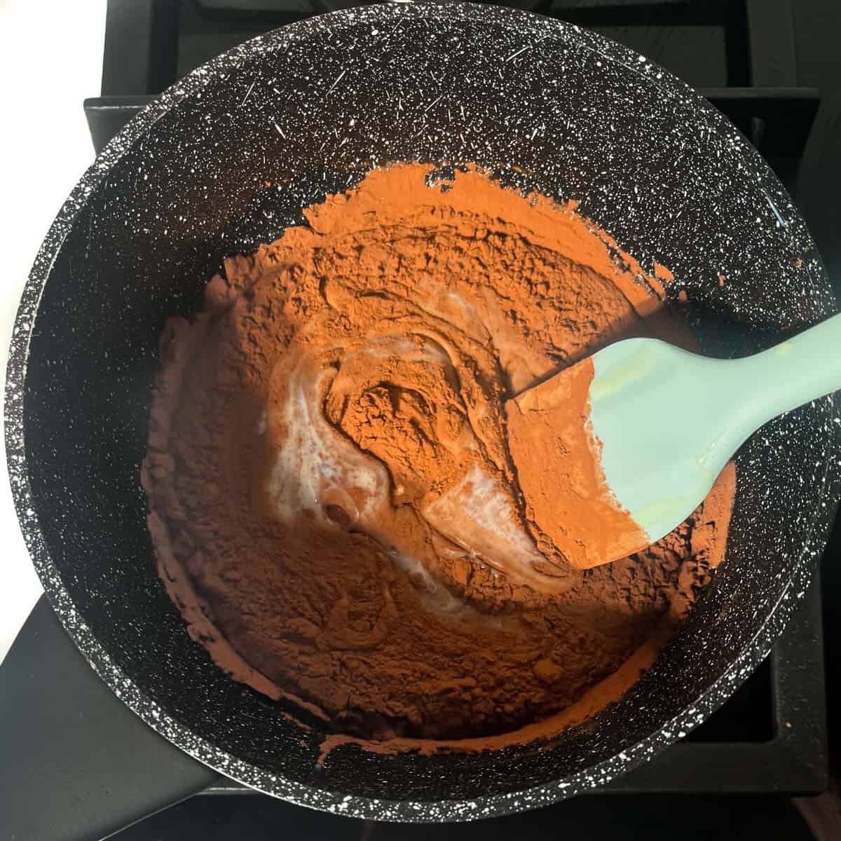 Stirring all the ingredients together for the brigadeiros in a medium saucepan.