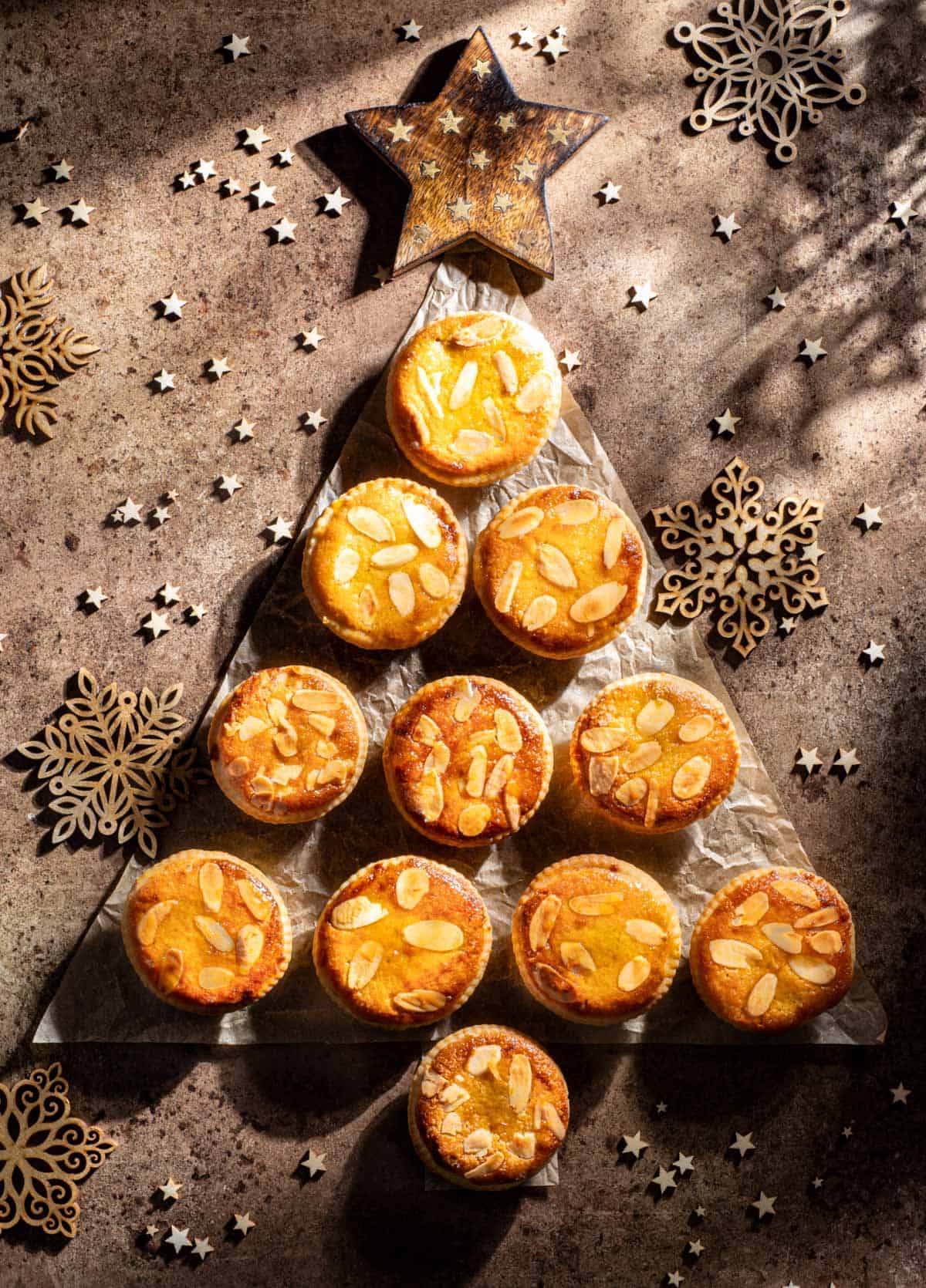 Frangipane mince pies packed in a Christmas tree shape on a brown background.