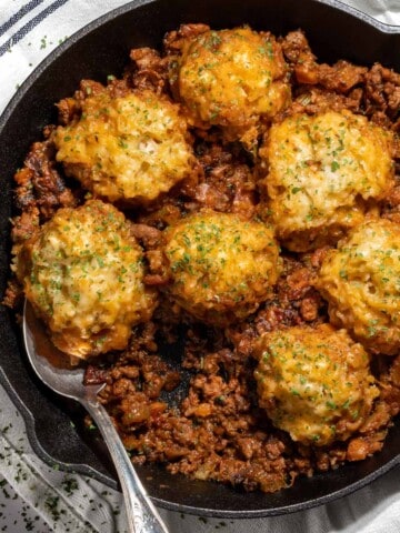 Mince and dumplings in a black skillet.