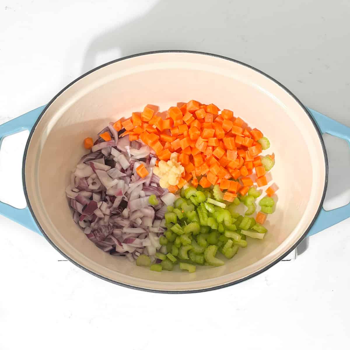 Adding all the vegetables for the mince and dumplings to a large pot.