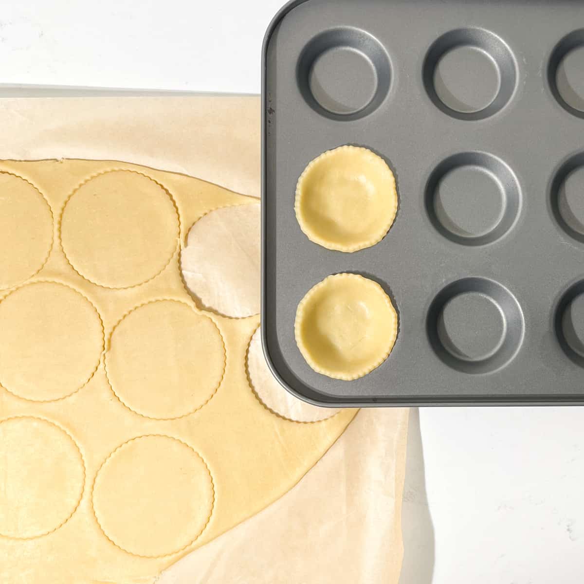 Cutting circles out of the mince pie pastry with a pastry cutter.