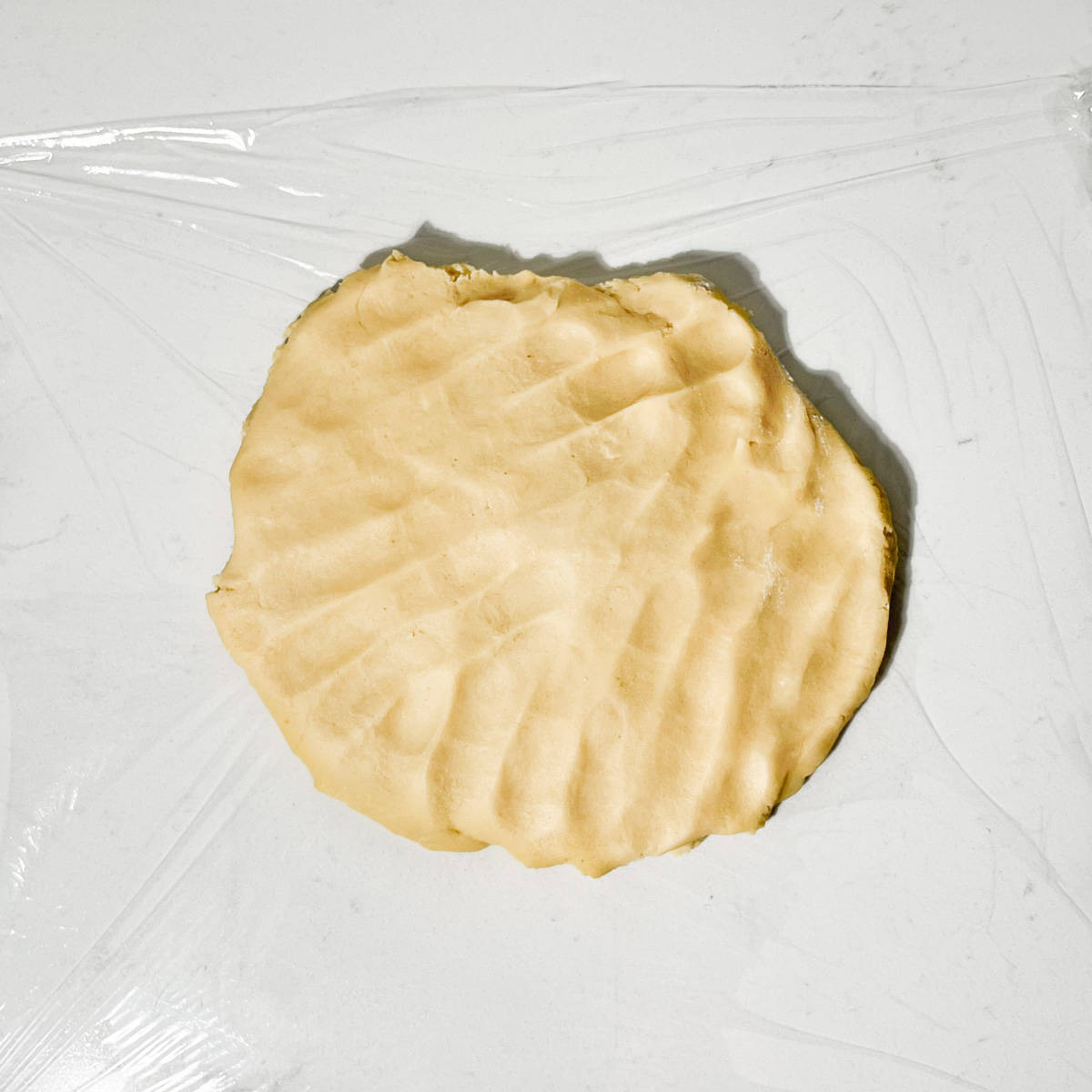 The pastry dough for frangipane mince pies on a piece of cling film.