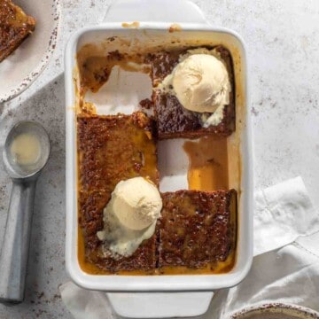 Malva pudding sliced into six squares with scoops of ice cream on top of the pudding.