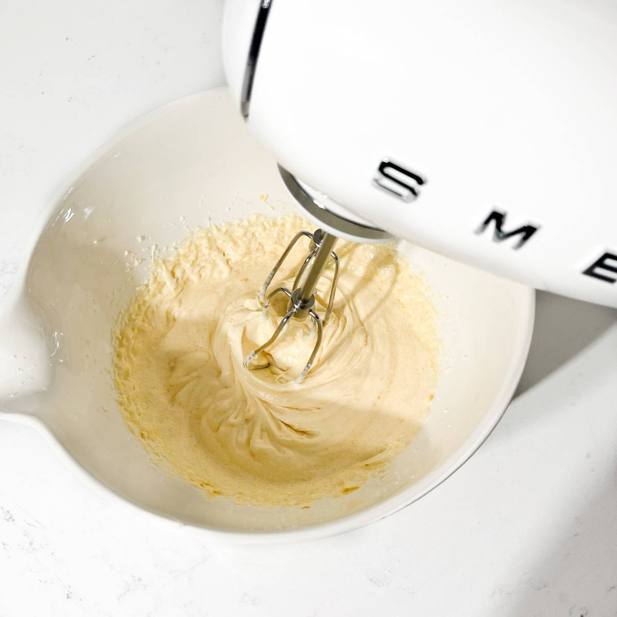 Beating ingredients until light and creamy with an electric hand mixer.