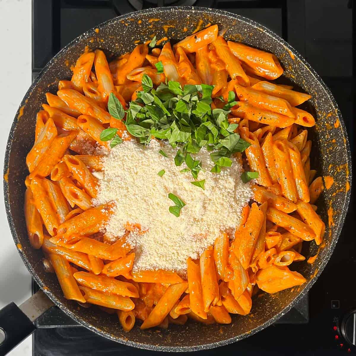 Adding parmesan and basil to the Gigi Hadid pasta.