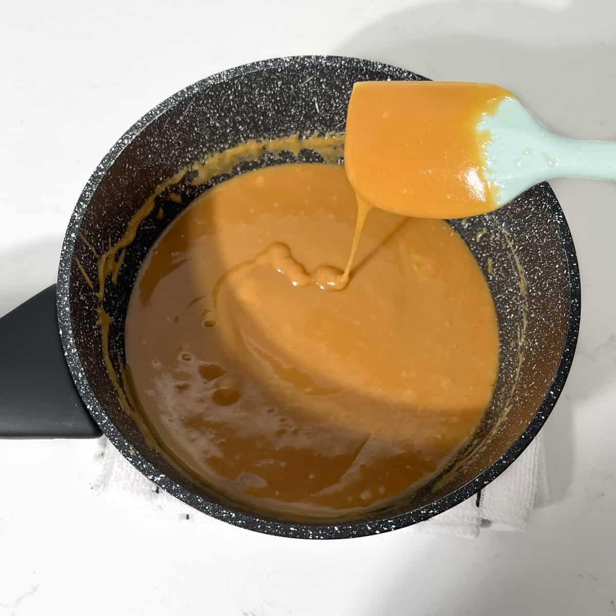 The consistency of the caramel layer after being boiled, looking thick and golden brown.