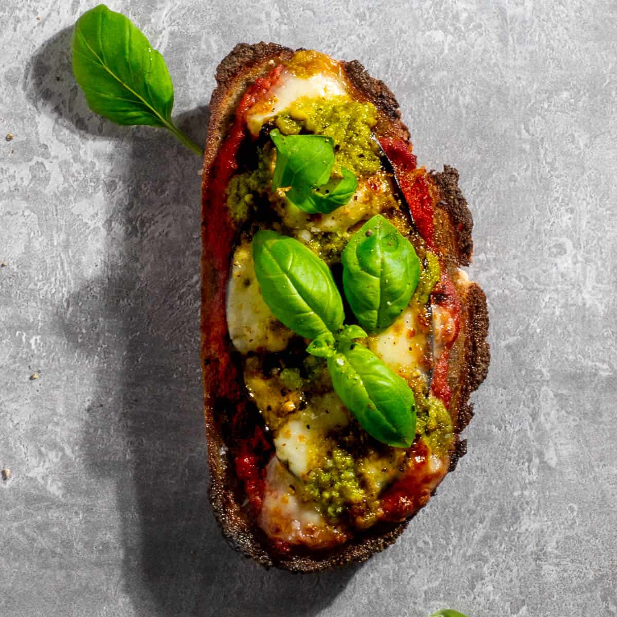 Aubergine/eggplant pizza toast on a grey background.