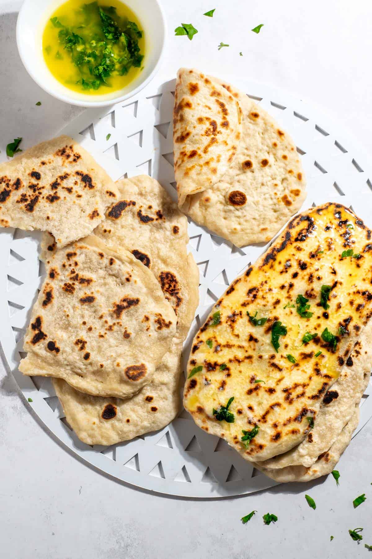 2 Ingredient flatbreads on a white tray with a bowl of parsley butter to the side.