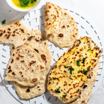 2 Ingredient flatbreads on a white tray with a bowl of parsley butter to the side.