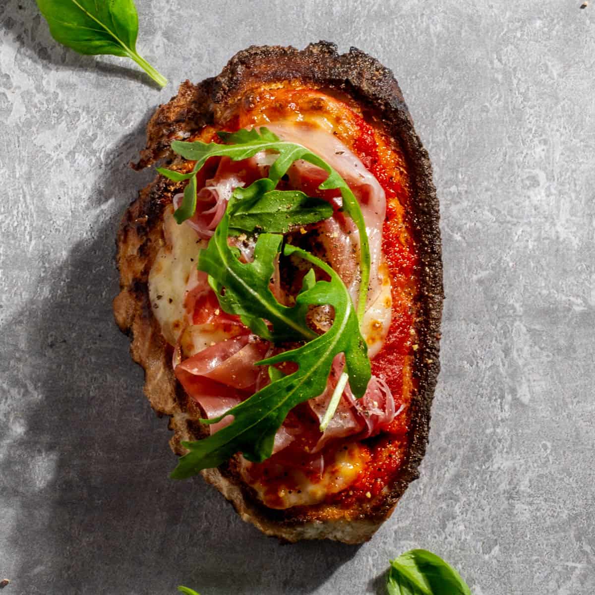 Parma ham pizza toast on a grey background.