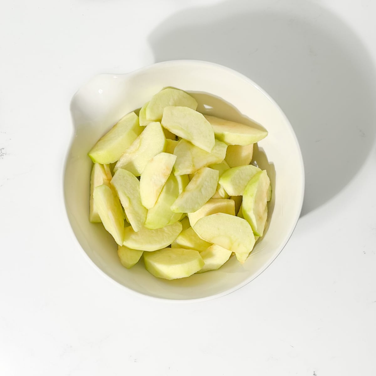 Sliced apples in a white bowl.