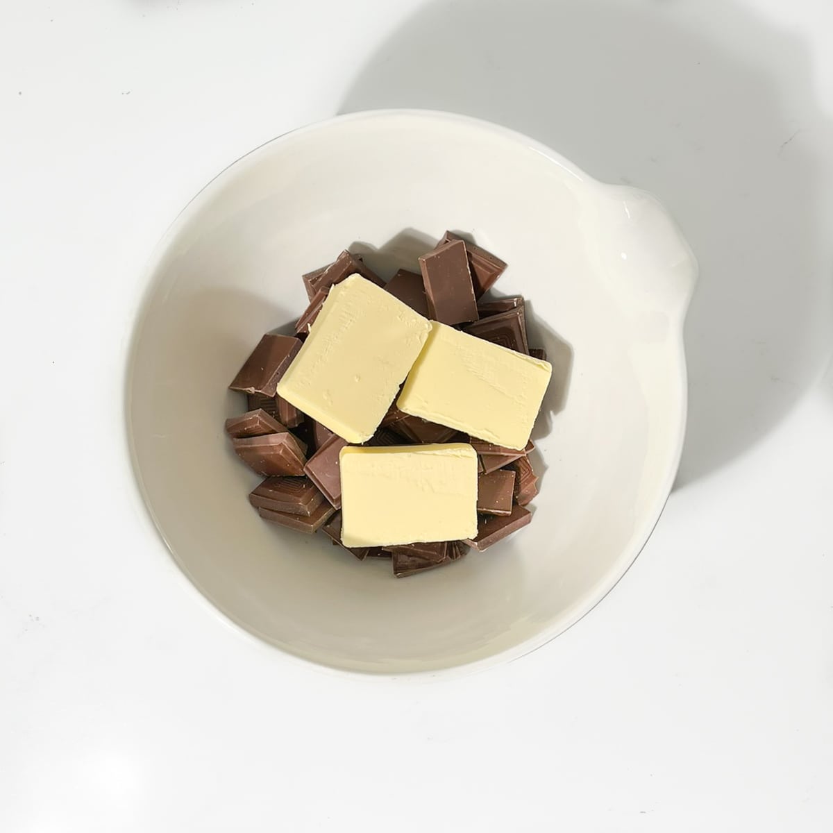 Chocolate and butter in a large white bowl.