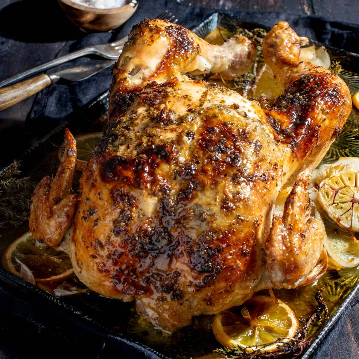 Whole Greek roast chicken on a baking tray.