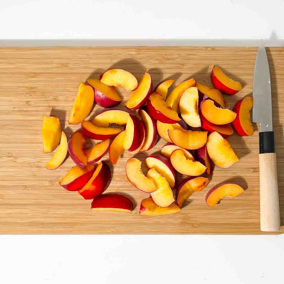 Sliced nectarines for the nectarine salad on a chopping board.