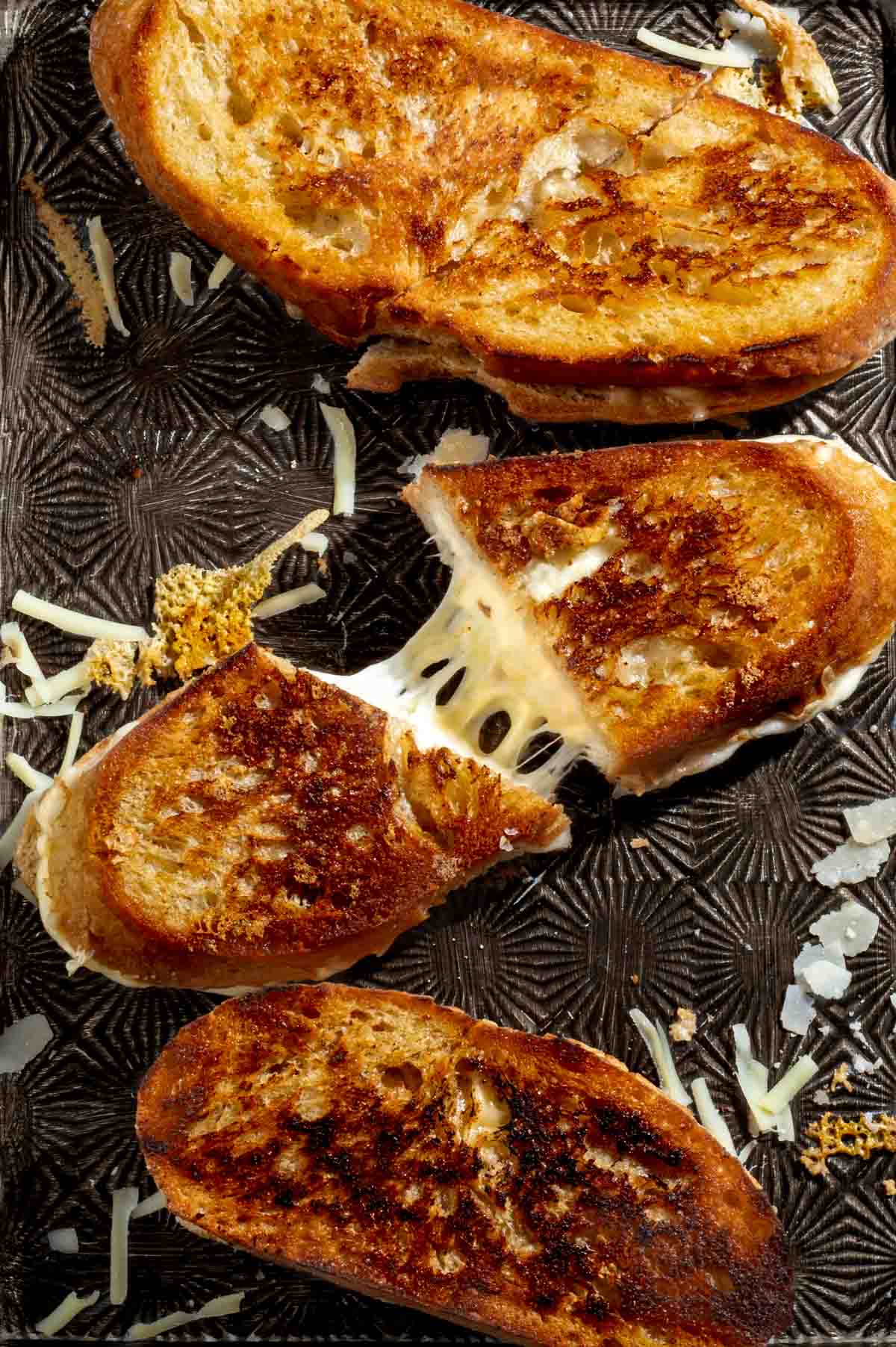 Sourdough grilled cheese sandwich sliced and pulled apart to show melted cheese inside.