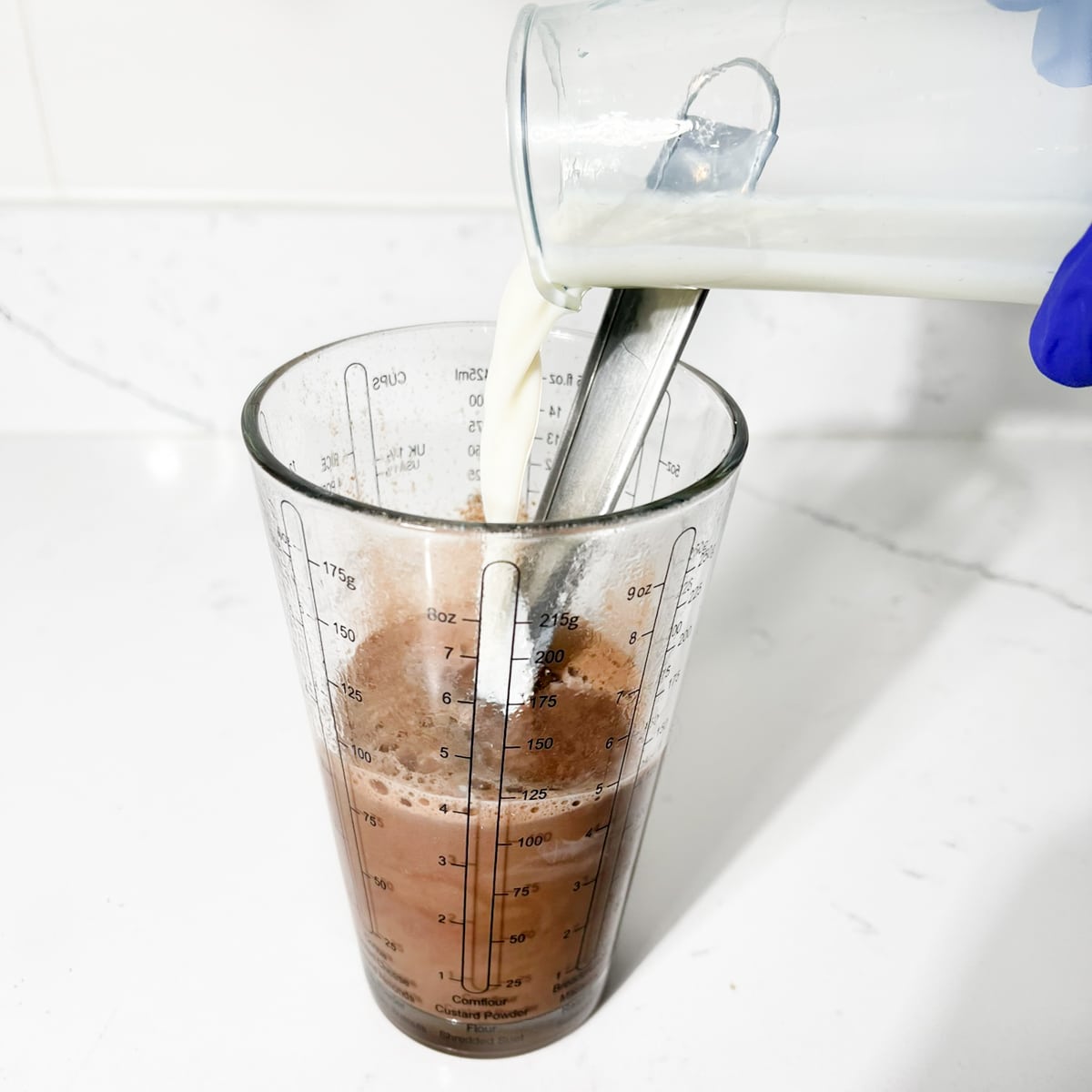 Adding the rest of the milk to the measuring cup.