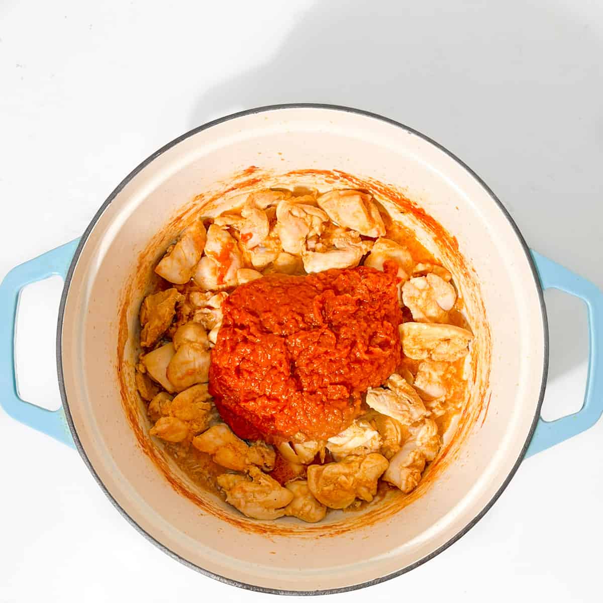 Adding the curry sauce to the chicken in the pan.